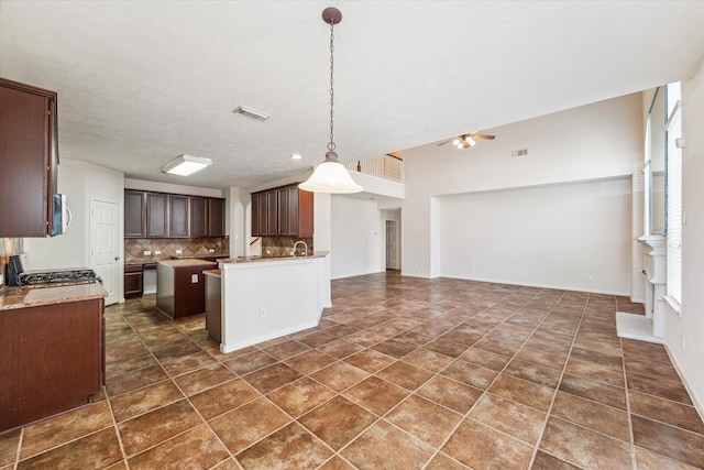 kitchen featuring pendant lighting, dark brown cabinetry, range, decorative backsplash, and ceiling fan