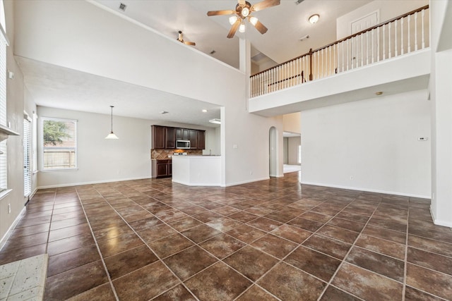 unfurnished living room with a towering ceiling and ceiling fan