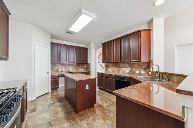 kitchen with stainless steel gas stove, dishwasher, sink, backsplash, and a kitchen island