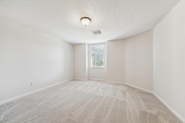 empty room with light carpet and a textured ceiling