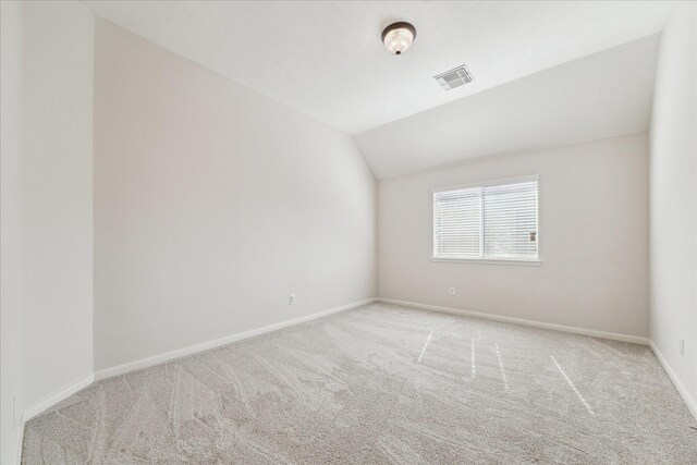 unfurnished room with light carpet and vaulted ceiling