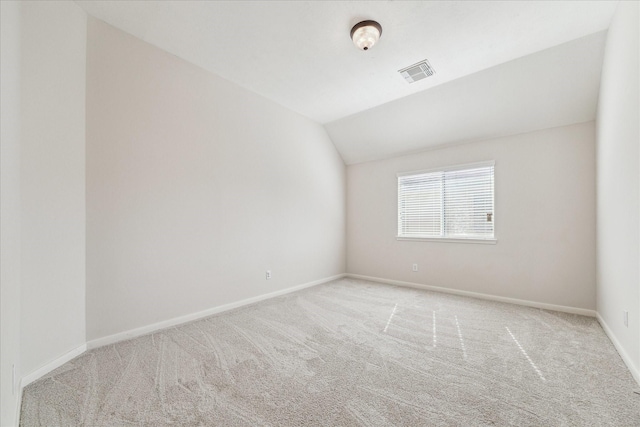 carpeted empty room with lofted ceiling