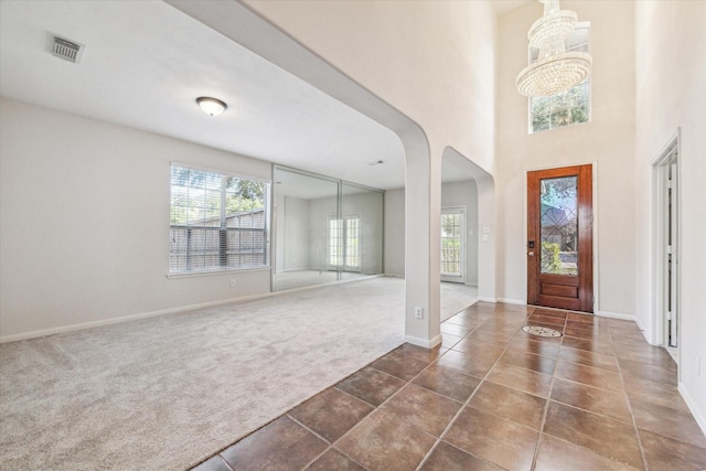 carpeted foyer with a notable chandelier