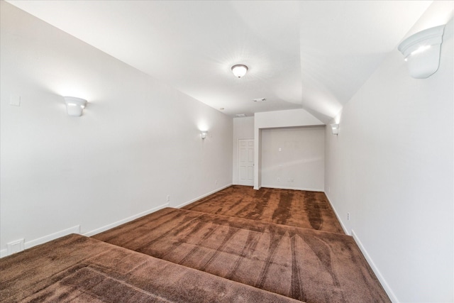 additional living space featuring vaulted ceiling and dark colored carpet