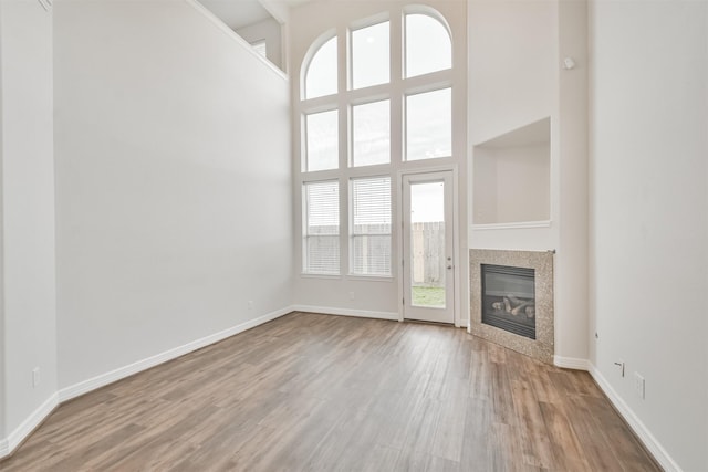 unfurnished living room featuring a high ceiling and light hardwood / wood-style flooring