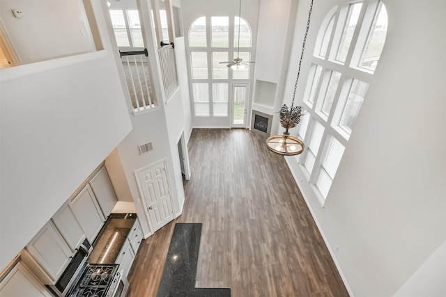 interior space with a towering ceiling, ceiling fan, and dark hardwood / wood-style floors