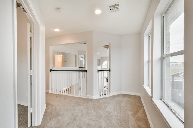 hall with a wealth of natural light and light carpet