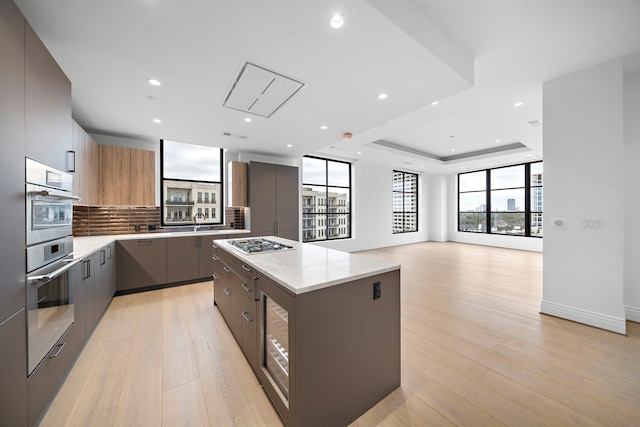 2323 San Felipe St Unit 803, Houston, TX 77019 - kitchen with a center island, a raised ceiling, light stone countertops, appliances with stainless steel finishes, and tasteful backsplash