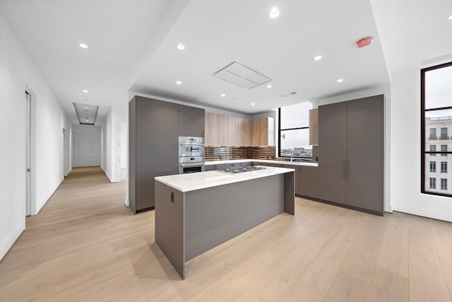 2323 San Felipe St Unit 803, Houston, TX 77019 - kitchen with appliances with stainless steel finishes, tasteful backsplash, light stone counters, light hardwood / wood-style flooring, and a center island