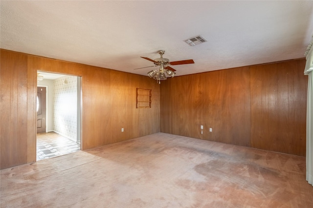 unfurnished room featuring wooden walls, carpet floors, and ceiling fan