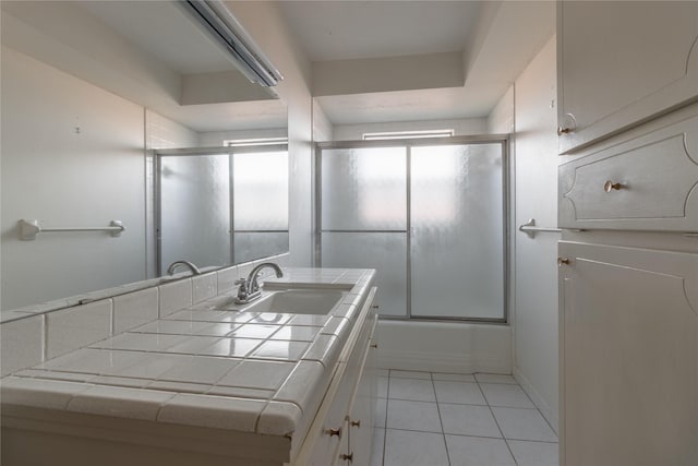 bathroom with tile patterned flooring, vanity, and bath / shower combo with glass door