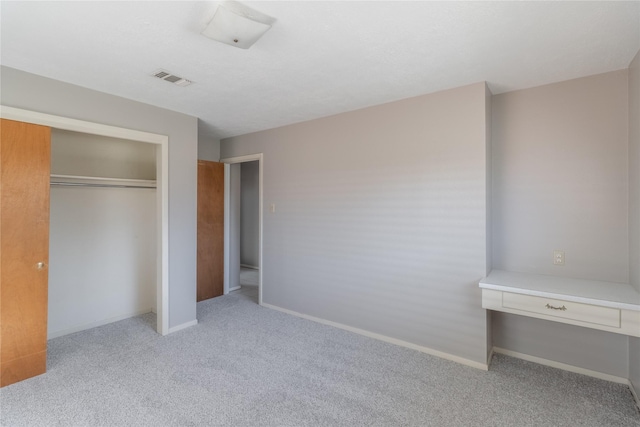 unfurnished bedroom featuring a closet and light colored carpet