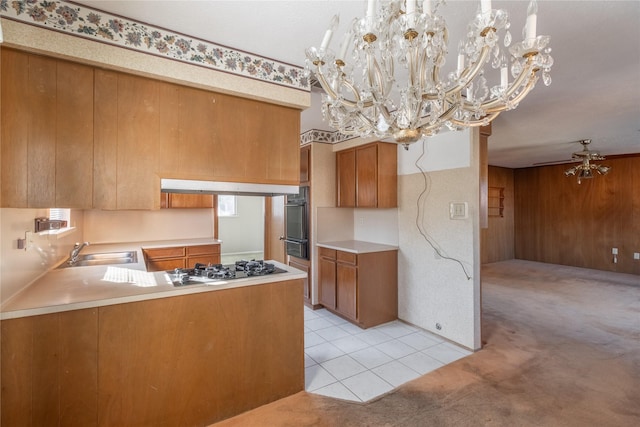 kitchen with sink, stainless steel gas cooktop, kitchen peninsula, a chandelier, and light tile patterned flooring