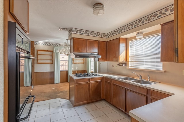 kitchen with kitchen peninsula, a textured ceiling, sink, light tile patterned floors, and stainless steel gas stovetop