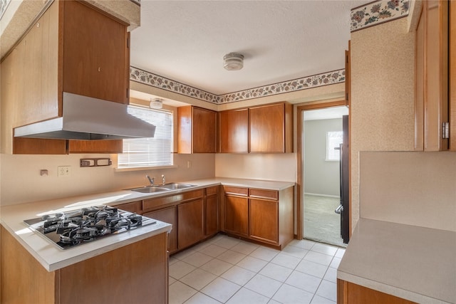 kitchen featuring light tile patterned floors, range hood, stainless steel gas cooktop, and sink