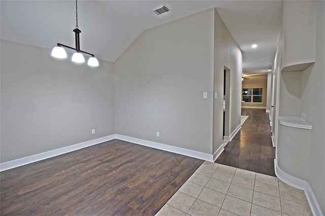 unfurnished dining area with tile patterned flooring and vaulted ceiling