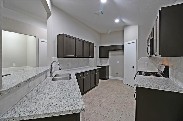 kitchen with light stone countertops, appliances with stainless steel finishes, tasteful backsplash, sink, and light tile patterned flooring