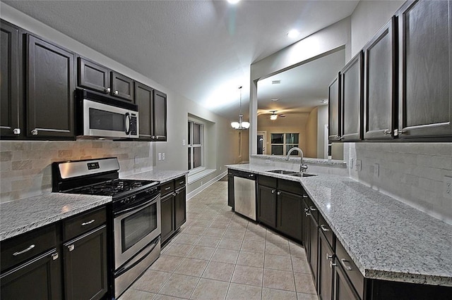 kitchen featuring backsplash, sink, light tile patterned floors, decorative light fixtures, and stainless steel appliances