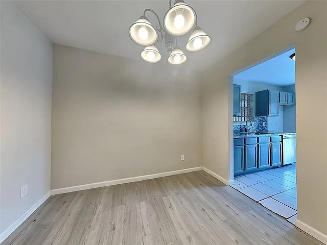 unfurnished dining area featuring light hardwood / wood-style flooring, an inviting chandelier, and sink