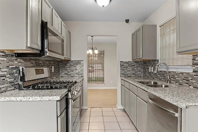 kitchen with appliances with stainless steel finishes, gray cabinetry, sink, light tile patterned floors, and a notable chandelier