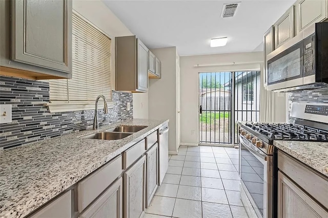 kitchen featuring decorative backsplash, appliances with stainless steel finishes, light stone counters, sink, and light tile patterned floors