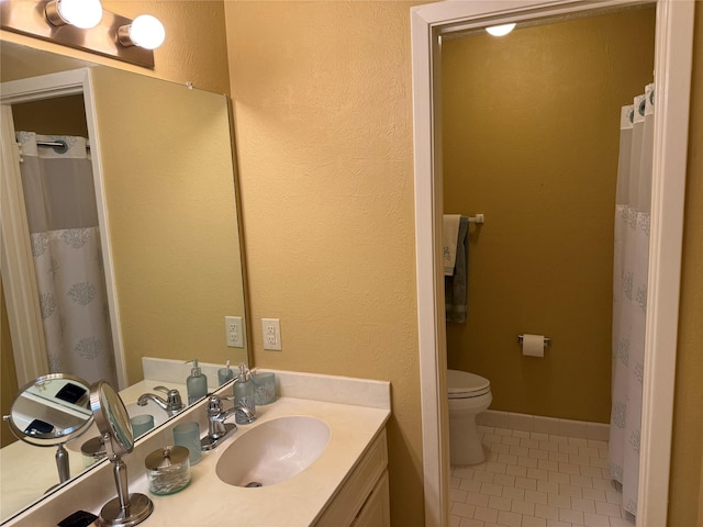 bathroom with tile patterned flooring, vanity, and toilet