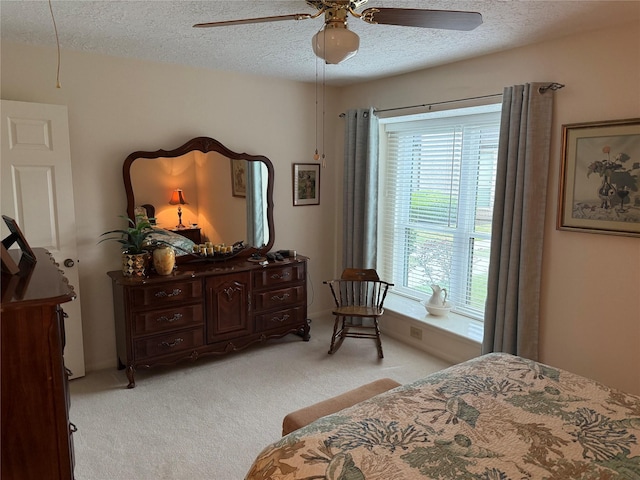 carpeted bedroom featuring ceiling fan and a textured ceiling