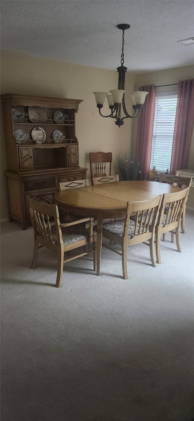 carpeted dining area featuring a textured ceiling and a notable chandelier