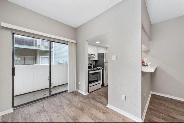 interior space featuring appliances with stainless steel finishes, light hardwood / wood-style floors, and white cabinets