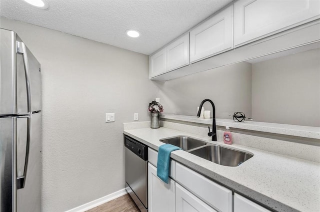 kitchen with white cabinets, a textured ceiling, appliances with stainless steel finishes, and sink