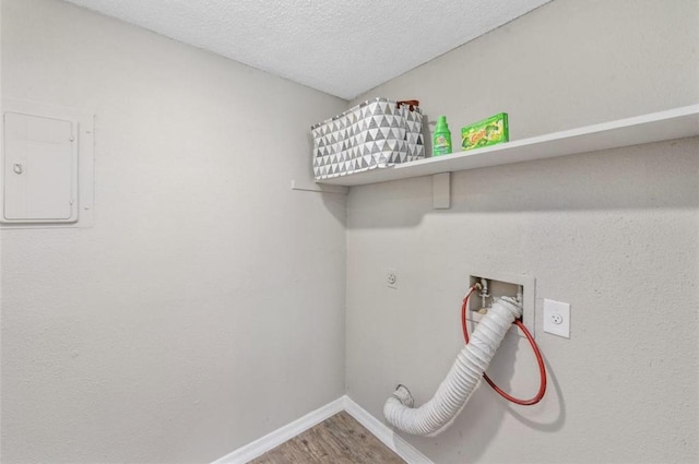 clothes washing area featuring electric panel, hardwood / wood-style flooring, washer hookup, a textured ceiling, and hookup for an electric dryer