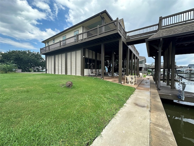 back of property with a balcony, a patio area, a yard, and a water view