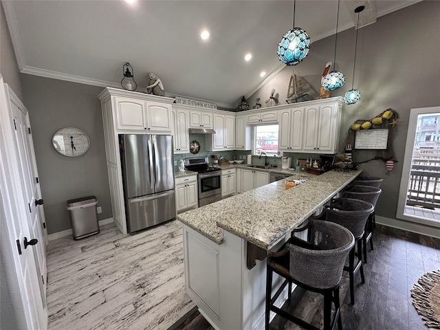 kitchen with kitchen peninsula, appliances with stainless steel finishes, a breakfast bar, sink, and white cabinetry