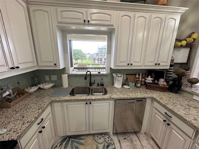 kitchen featuring backsplash, light stone counters, stainless steel dishwasher, sink, and white cabinetry