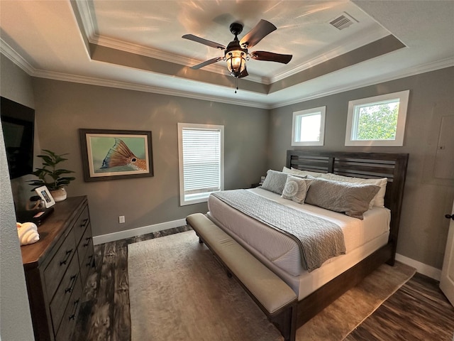 bedroom with dark wood-type flooring, a raised ceiling, ceiling fan, and ornamental molding