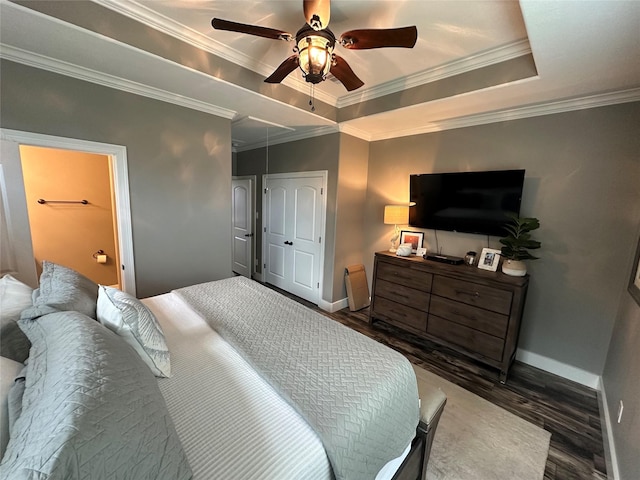 bedroom with crown molding, ceiling fan, a tray ceiling, dark hardwood / wood-style flooring, and a closet