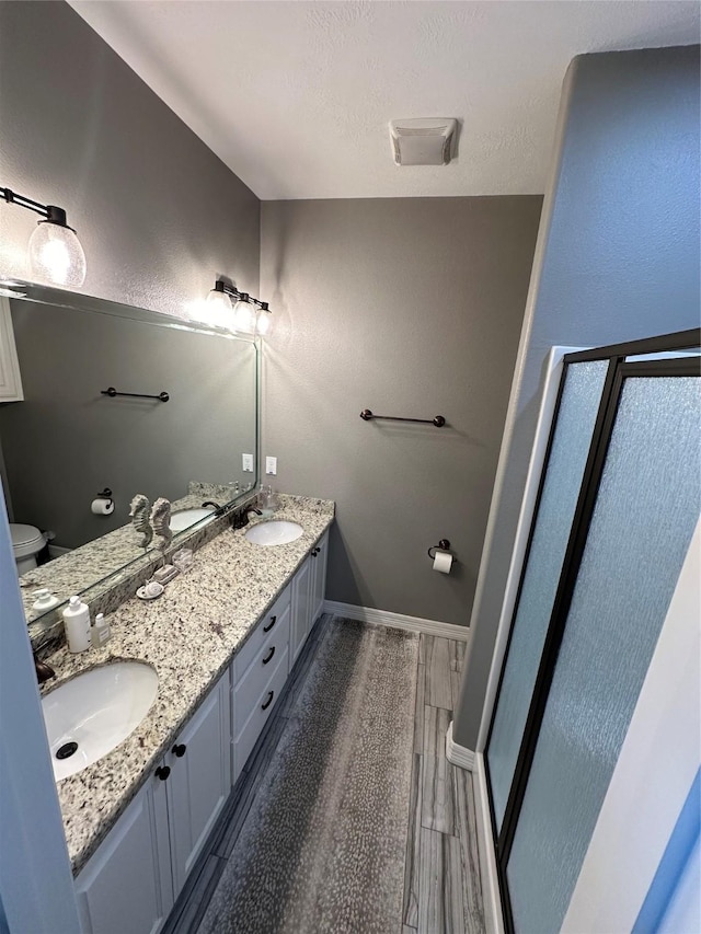 bathroom featuring wood-type flooring, vanity, toilet, and an enclosed shower