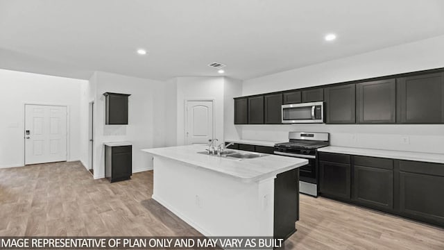 kitchen with a kitchen island with sink, sink, light hardwood / wood-style flooring, and appliances with stainless steel finishes