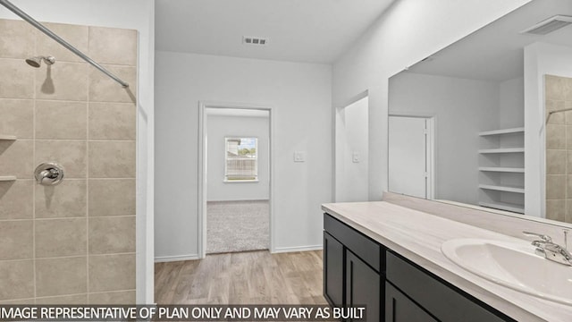 bathroom featuring a tile shower, vanity, and hardwood / wood-style flooring