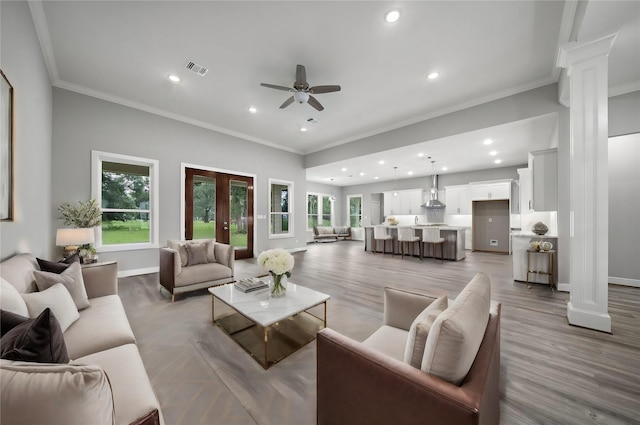 living room with ornamental molding, decorative columns, and a healthy amount of sunlight