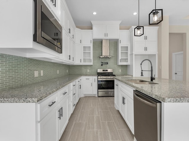 kitchen featuring white cabinetry, sink, wall chimney range hood, tasteful backsplash, and appliances with stainless steel finishes