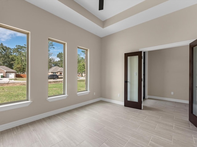 spare room featuring ceiling fan, a healthy amount of sunlight, a tray ceiling, and french doors