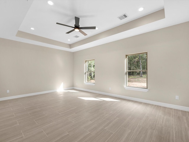 spare room featuring a tray ceiling and ceiling fan