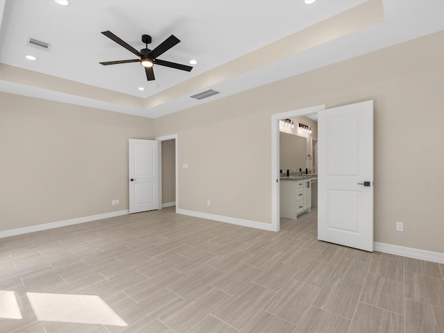 interior space with ensuite bathroom, a raised ceiling, and ceiling fan