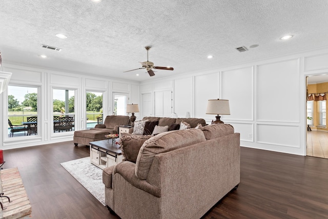 living room featuring ceiling fan, a textured ceiling, and dark wood-type flooring