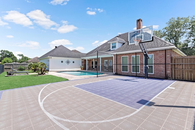 view of basketball court with a fenced in pool and a yard