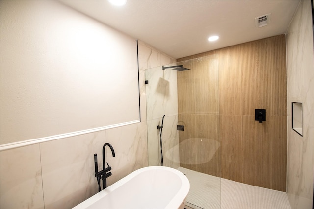 bathroom featuring shower with separate bathtub and tile walls