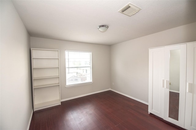 unfurnished room featuring dark hardwood / wood-style flooring and a textured ceiling