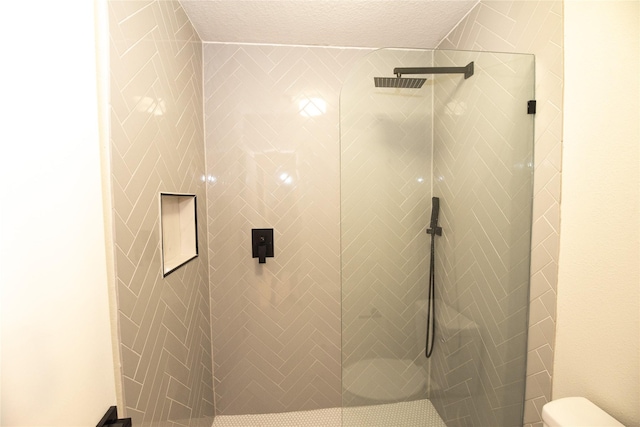 bathroom featuring toilet, a textured ceiling, and tiled shower