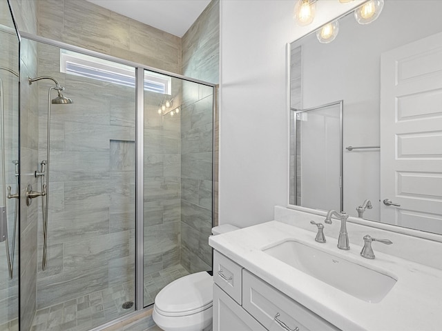 bathroom featuring toilet, vanity, and a shower with door